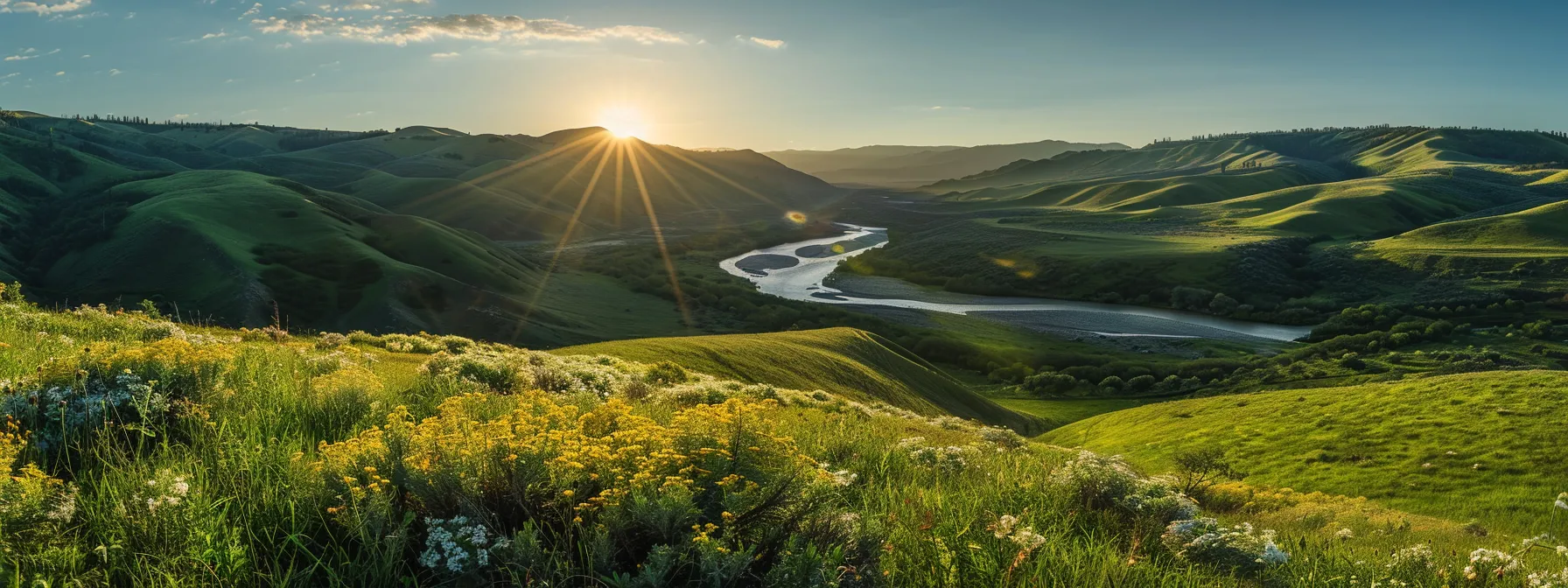 a breathtaking landscape unfolds as golden sun rays cascade over vibrant green hills, with a tranquil river meandering through a field of wildflowers under a brilliant blue sky.