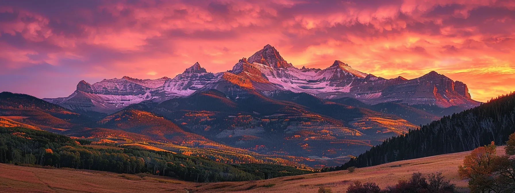 a breathtaking sunrise casts golden light over a serene mountain landscape, highlighting the rugged peaks that tower majestically against a canvas of vibrant pink and orange skies.