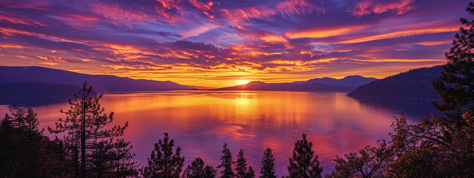a breathtaking sunset casts a warm, golden glow across a tranquil lake, reflecting vibrant hues of orange and purple while silhouetted trees frame the scene against a serene sky.