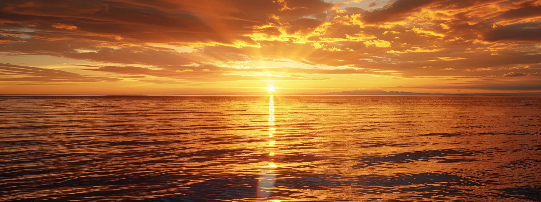 a breathtaking sunset over a calm ocean, casting golden and crimson hues across the sky, perfectly reflecting on the tranquil water's surface.