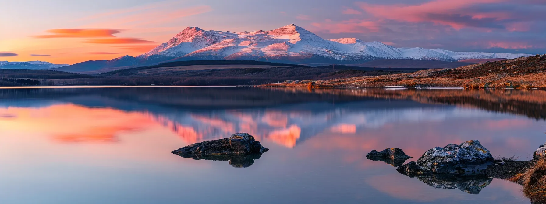 a majestic mountain landscape at sunrise, with vibrant orange and pink hues illuminating the snow-capped peaks and a serene lake reflecting the stunning colors.