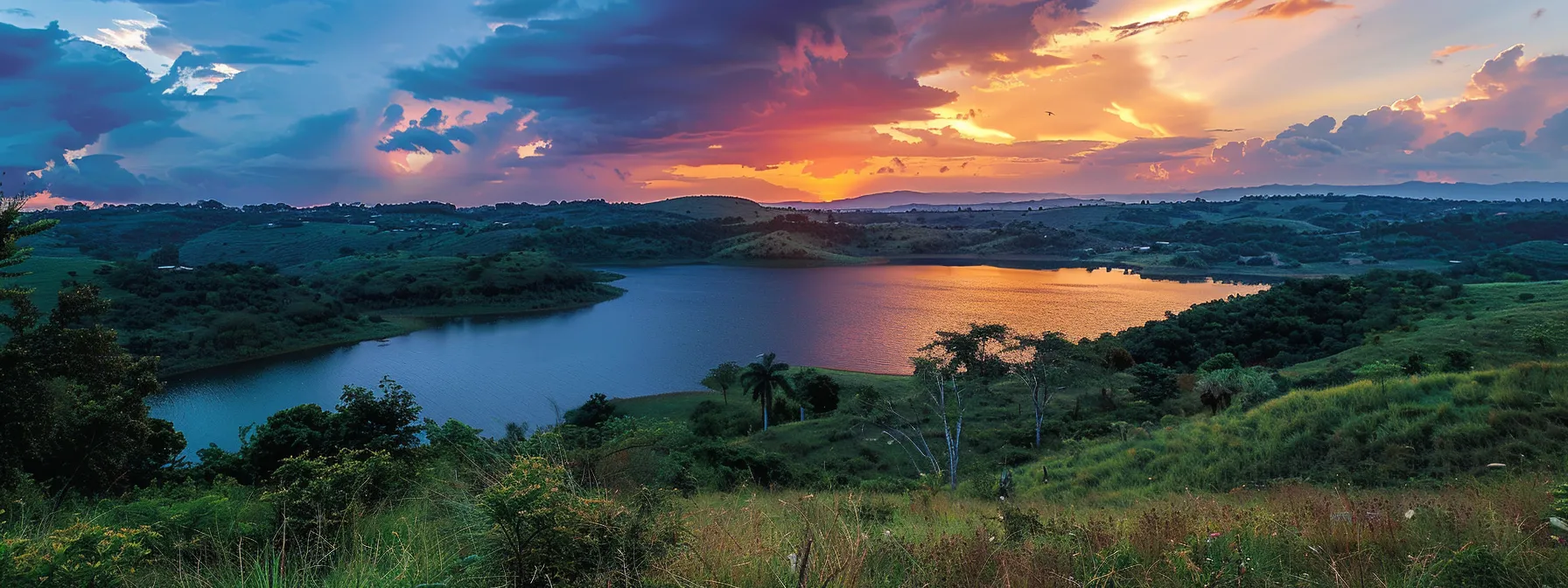 a serene sunset paints the sky in vibrant hues of orange and pink, casting a warm glow over a tranquil lake nestled among lush green hills.