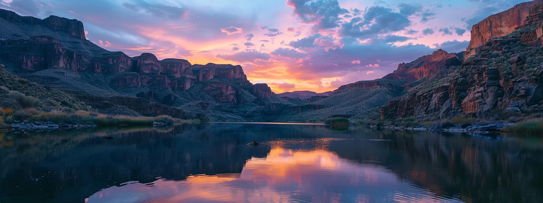a vibrant sunset casts a warm glow over a tranquil lake surrounded by towering mountains, reflecting the rich colors of the sky on the glassy surface of the water.