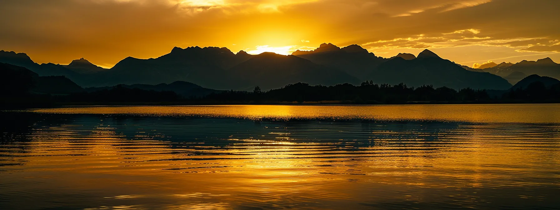 a vibrant sunset casts a warm golden glow over a tranquil lake, with silhouetted mountains rising majestically in the background, creating a serene and harmonious atmosphere.