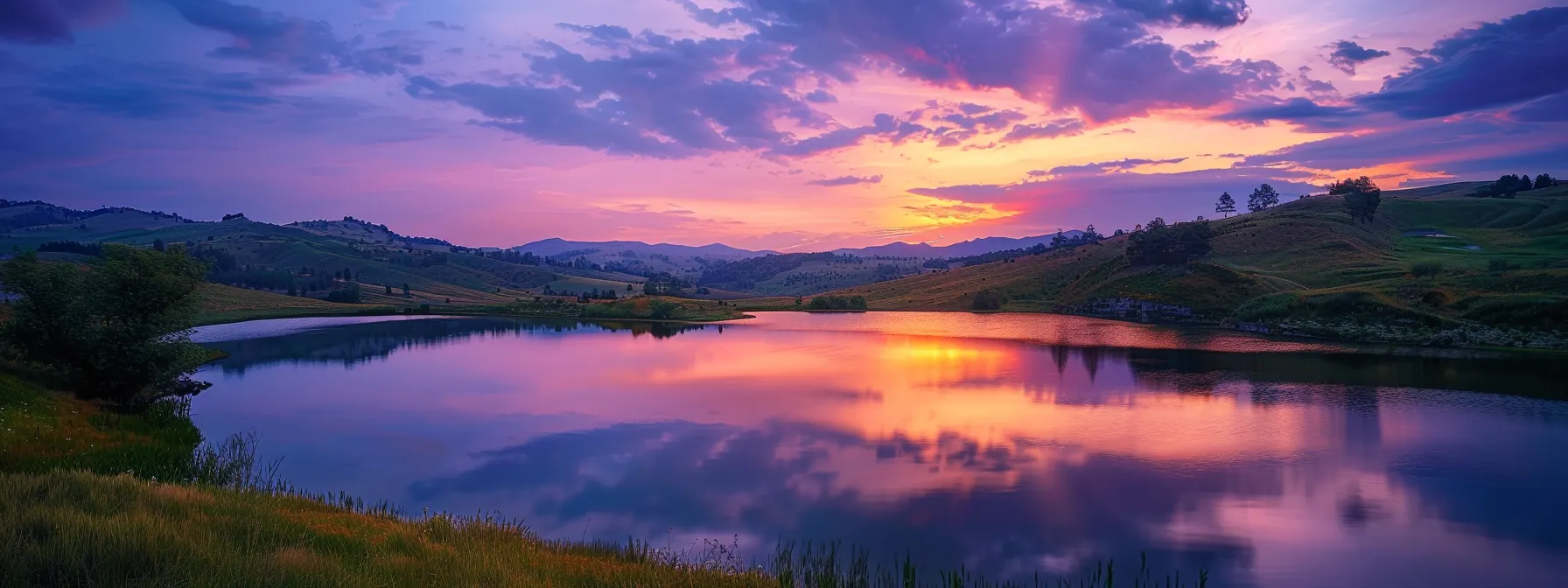 a vibrant sunset paints the sky in dramatic hues of orange and purple, casting a golden glow over a serene landscape of lush rolling hills and a tranquil lake reflecting the stunning sky.