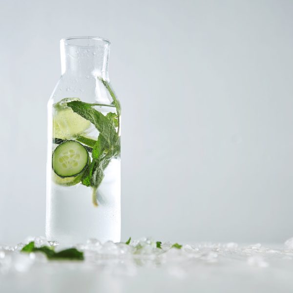 Vintage glass bottle filled with cold fresh cucumber mint lime lemonade like mojito witount alcohol, ideal drink for summer isolated on table with melted ice